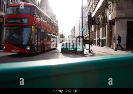 Ein Bus fährt am 15. Oktober 2020 auf dem Piccadilly in London, England, an einem ungenutzten, vorübergehend ausgebauten Straßenbelag vorbei, der zur Unterstützung der sozialen Distanzierung gedacht war. London wird ab diesem Wochenende unter die „Tier 2“-Coronavirus-Sperrmaßnahmen fallen, die ein Verbot für Menschen aus verschiedenen Haushalten einführen werden, überall in Innenräumen zu mischen, was besondere Sorge für die bereits stark betroffene Hotellerie bedeutet. In mehreren anderen Teilen des Landes sollen auch die Covid-19-Beschränkungen ähnlich verschärft werden. Das dreistufige System für England trat diese Woche in Kraft, mit jedem Bereich des CO Stockfoto