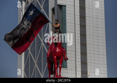 Eine Person hält eine chilenische Flagge auf der Statue auf der Plaza Dignidad. Inmitten der Demonstration und des Protests gegen die Regierung von Sebastián Piñera, soziale Ungleichheit und das neoliberale System. Am 16. Oktober 2020 in Santiago de Chile, Chile. (Foto von Claudio Abarca Sandoval/NurPhoto) Stockfoto