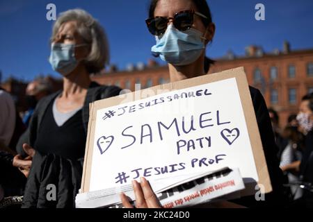 Eine Frau hält ein Plakat mit der Aufschrift 'Ich bin Samuel Paty, #Imateacher'. Mit einem Band in den französischen Farben. Nach der Tötung von Samuel Paty, Lehrer für Geographie-Geschichte, in Conflans-Sainte-Honorine (Yvelines) am 16.. Oktober versammelten sich mehrere Tausende von Menschen auf dem Hauptplatz von Toulouse, vor dem Rathaus, dem Capitole, um die Meinungsfreiheit zu verteidigen und Samuel zu ehren. Einige Leute kamen mit einem Cover von Charlie Hebdo, da der Lehrer getötet wurde, nachdem er seinen Schülern die Karikaturen von Charlie Hebdo von Muhammed gezeigt hatte. Der Mörder wurde anschließend von der französischen Polizei getötet. Ein Stockfoto