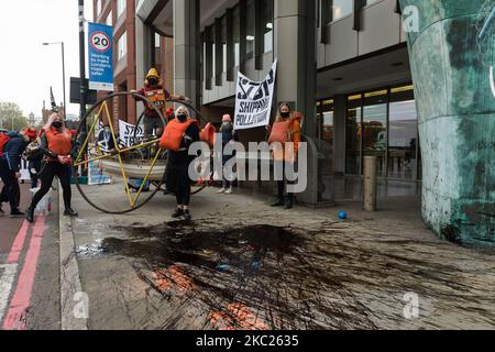 Aktivisten der Ocean Rebellion verschütteten das gefälschte Öl während eines Protestes vor dem Hauptquartier der Internationalen Seeschifffahrtsorganisation der Vereinten Nationen am Eröffnungstag der Verhandlungen über die Reduzierung der Treibhausgasemissionen aus der Schifffahrt am 19. Oktober 2020 in London, England. Die Demonstranten heben die Verwüstungen hervor, die durch die jüngste Ölpest von MV Wakashio auf den Völkern und Ökosystemen von Mauritius verursacht wurden. Untätigkeit der IMO beim Schutz der Ozeane und des Klimas und der Nachfragesicherung auf emissionsfreie Frachtschiffe, um die Verschmutzung durch verschüttete fossile Brennstoffe und Treibhausgasemissionen durch die Schifffahrt zu verhindern i Stockfoto