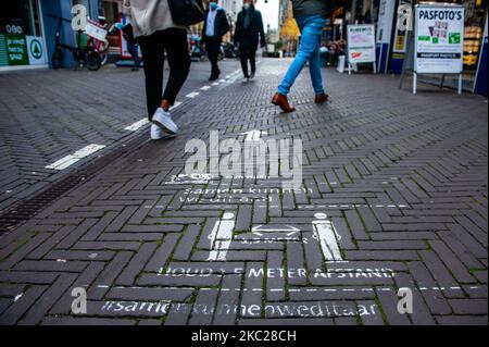 Ein Schild auf dem Boden weist auf soziale Distanz hin, während einer teilweisen Sperrung in Den Haag, Niederlande, am 20.. Oktober 2020. (Foto von Romy Arroyo Fernandez/NurPhoto) Stockfoto