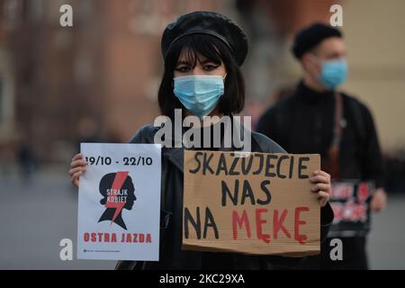 Die pro-Choice-Aktivistin hält ein Plakat mit dem Aufdruck „Women Strike“ und ein Schild mit der Aufschrift „You verurteile US to Suffering“ im Zentrum von Krakau, einem Teil der Roten Zone des Coronavirus, während eines Protestes gegen ein Gesetz, das Abtreibung für irreversible Schäden am Feten verbietet. Morgen, am Donnerstag, dem 22. Oktober, wird das Verfassungsgericht den Antrag einer Gruppe von Abgeordneten der Partei für Recht und Gerechtigkeit (PiS) zur Verfassungsmäßigkeit der sogenannten eugenischen Abtreibung prüfen, die im Falle des Verdachts auf die Krankheit eines Kindes oder dessen Beeinträchtigung durchgeführt wird. Eine Gruppe von PiS-Abgeordneten reichte einen Antrag an t Stockfoto