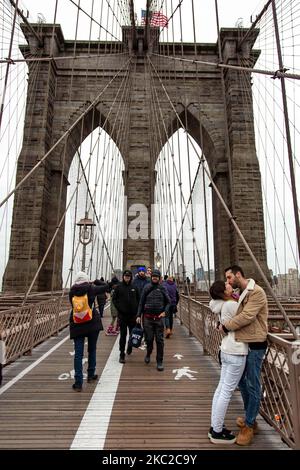 Ein junges Paar, das sich auf der berühmten Brooklyn Bridge in New York City in den Vereinigten Staaten küsst, wie es an einem bewölkten Tag mit Touristen und Einheimischen zu sehen ist. Die berühmte Brücke, ein Wahrzeichen für NYC und die Vereinigten Staaten von Amerika, ist eine hybride Hängebrücke mit Kabelgestellen, die den East River zwischen den Stadtteilen Manhattan und Brooklyn überspannt. Die historische NY Wahrzeichen Brücke wurde zwischen 1869 und 1883 gebaut. New York, USA am 13. Februar 2020 (Foto von Nicolas Economou/NurPhoto) Stockfoto