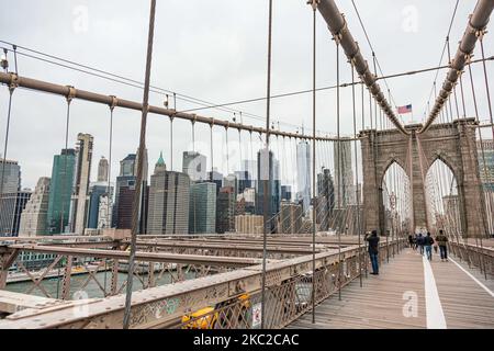 Blick von der Brooklyn Bridge auf Downtown Manhattan. Die Brooklyn Bridge in New York City in den Vereinigten Staaten, wie sie an einem bewölkten Tag mit Touristen und Einheimischen auf ihr zu sehen ist. Die berühmte Brücke, ein Wahrzeichen für NYC und die Vereinigten Staaten von Amerika, ist eine hybride Hängebrücke mit Kabelgestellen, die den East River zwischen den Stadtteilen Manhattan und Brooklyn überspannt. Die historische NY Wahrzeichen Brücke wurde zwischen 1869 und 1883 gebaut. New York, USA am 13. Februar 2020 (Foto von Nicolas Economou/NurPhoto) Stockfoto