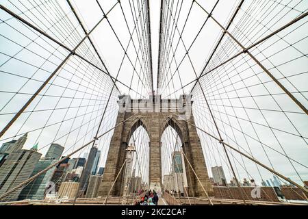 Blick von der Brooklyn Bridge auf Downtown Manhattan. Die Brooklyn Bridge in New York City in den Vereinigten Staaten, wie sie an einem bewölkten Tag mit Touristen und Einheimischen auf ihr zu sehen ist. Die berühmte Brücke, ein Wahrzeichen für NYC und die Vereinigten Staaten von Amerika, ist eine hybride Hängebrücke mit Kabelgestellen, die den East River zwischen den Stadtteilen Manhattan und Brooklyn überspannt. Die historische NY Wahrzeichen Brücke wurde zwischen 1869 und 1883 gebaut. New York, USA am 13. Februar 2020 (Foto von Nicolas Economou/NurPhoto) Stockfoto