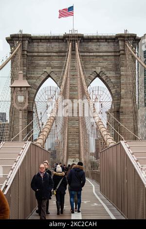 Die Brooklyn Bridge in New York City in den Vereinigten Staaten, wie sie an einem bewölkten Tag mit Touristen und Einheimischen auf ihr zu sehen ist. Die berühmte Brücke, ein Wahrzeichen für NYC und die Vereinigten Staaten von Amerika, ist eine hybride Hängebrücke mit Kabelgestellen, die den East River zwischen den Stadtteilen Manhattan und Brooklyn überspannt. Die historische NY Wahrzeichen Brücke wurde zwischen 1869 und 1883 gebaut. New York, USA am 13. Februar 2020 (Foto von Nicolas Economou/NurPhoto) Stockfoto