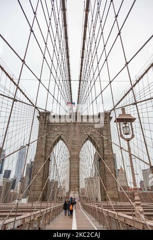 Blick von der Brooklyn Bridge auf Downtown Manhattan. Die Brooklyn Bridge in New York City in den Vereinigten Staaten, wie sie an einem bewölkten Tag mit Touristen und Einheimischen auf ihr zu sehen ist. Die berühmte Brücke, ein Wahrzeichen für NYC und die Vereinigten Staaten von Amerika, ist eine hybride Hängebrücke mit Kabelgestellen, die den East River zwischen den Stadtteilen Manhattan und Brooklyn überspannt. Die historische NY Wahrzeichen Brücke wurde zwischen 1869 und 1883 gebaut. New York, USA am 13. Februar 2020 (Foto von Nicolas Economou/NurPhoto) Stockfoto