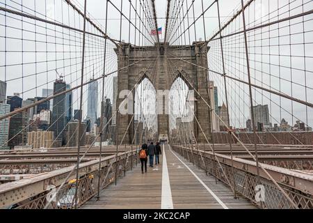 Blick von der Brooklyn Bridge auf Downtown Manhattan. Die Brooklyn Bridge in New York City in den Vereinigten Staaten, wie sie an einem bewölkten Tag mit Touristen und Einheimischen auf ihr zu sehen ist. Die berühmte Brücke, ein Wahrzeichen für NYC und die Vereinigten Staaten von Amerika, ist eine hybride Hängebrücke mit Kabelgestellen, die den East River zwischen den Stadtteilen Manhattan und Brooklyn überspannt. Die historische NY Wahrzeichen Brücke wurde zwischen 1869 und 1883 gebaut. New York, USA am 13. Februar 2020 (Foto von Nicolas Economou/NurPhoto) Stockfoto