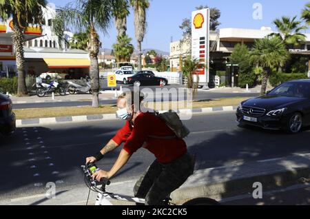 Frau in Schutzmaske fährt mit dem Fahrrad am Wasser in Limassol. Zypern, Freitag, 23. Oktober 2020 Zypern hat das Tragen von Masken für Personen über 12 Jahren in allen öffentlichen Bereichen im Freien obligatorisch gemacht und hat in zwei seiner sechs Bezirke eine Nachtruhe verhängt, nachdem die COVID-19-Fälle, bei denen tägliche Infektionen in den letzten zwei Wochen Rekordzahlen erreichten, stark angestiegen sind. (Foto von Danil Shamkin/NurPhoto) Stockfoto