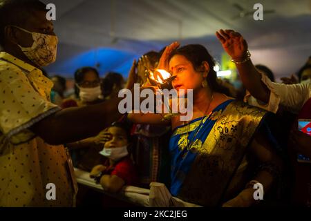 Die Menschen nehmen Segen vom Mönch, um zu feiern, dass Durga Puja, das größte religiöse Fest der bengalischen Hindu-Gemeinschaft, am Donnerstag mit dem Maha Sashtha Puja in Tempeln im ganzen Land begonnen hat. Am 25. Oktober 2020 in Dhaka, Bangladesch. (Foto von Istiak Karim/NurPhoto) Stockfoto