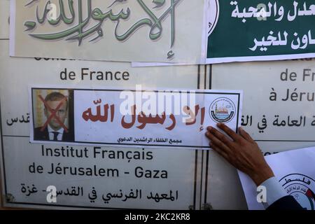 Ein Palästinenser legt vor dem französischen Kulturzentrum in Gaza-Stadt am 26. Oktober 2020 Transparente auf, auf denen durchgestrichene Bilder des französischen Präsidenten Emmanuel Macron zu sehen sind, während er gegen die Veröffentlichung eines Zeichentrickfilms des Propheten Mohammed in Frankreich und Macrons Kommentare protestierte. (Foto von Majdi Fathi/NurPhoto) Stockfoto