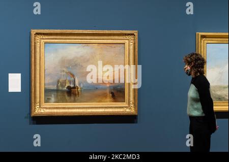 (NUR ZUR REDAKTIONELLEN VERWENDUNG) Ein Mitarbeiter der Galerie steht neben „The Fighting Temeraire, zerrissen an ihren letzten Liegeplatz, um aufgelöst zu werden“, 1838 von JMW Turner (1775-1851) während einer Fotoausstellung zur Förderung der Eröffnung der Ausstellung „Turner's Modern World“ in der Tate Britain (28. Oktober 2020 - 7. März 2021) Am 26. Oktober 2020 in London, England, dem größten britischen Landschaftsmaler gewidmet. (Foto von Wiktor Szymanowicz/NurPhoto) Stockfoto