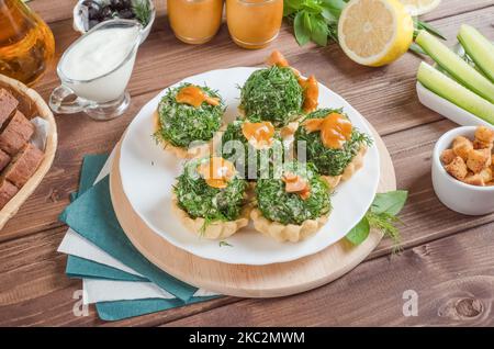 Tartlets, gefüllt mit Rindfleisch, Champignons und Kartoffeln mit Gemüse auf einem weißen Teller auf dunklem Holzboden. Stockfoto