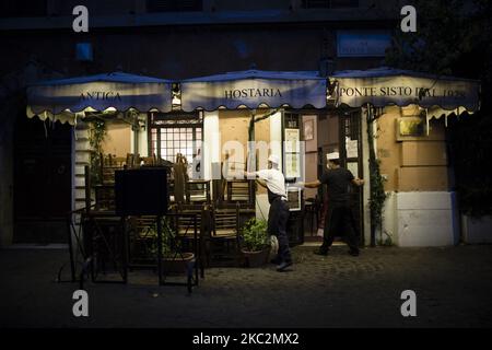 Mitarbeiter schließen ein Restaurant im Stadtteil Trastevere, da Italien mit einem Anstieg der Infektionen mit dem Coronavirus (COVID-19) konfrontiert ist. Rom, Italien, 26. Oktober 2020. Die italienische Regierung hat neue landesweite Covid-19-Beschränkungen beschlossen, die am 26. Oktober in Kraft treten und die Schließung von Restaurants und Bars bis 6pm sowie die Schließung von Fitnessstudios, Kinos und Schwimmbädern umfassen. Nach Angaben des Gesundheitsministeriums gab es in den letzten 24 Stunden von 124.686 durchgeführten Tampons 17.012 Infektionen mit Covid-19. 141 Todesfälle und 76 weitere Patienten wurden auf Intensivstationen aufgenommen. (Foto von Christian Min Stockfoto