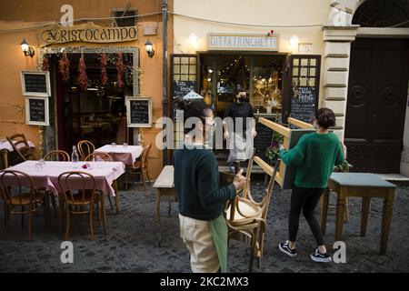 Mitarbeiter schließen ein Restaurant im Stadtteil Trastevere, da Italien mit einem Anstieg der Infektionen mit dem Coronavirus (COVID-19) konfrontiert ist. Rom, Italien, 26. Oktober 2020. Die italienische Regierung hat neue landesweite Covid-19-Beschränkungen beschlossen, die am 26. Oktober in Kraft treten und die Schließung von Restaurants und Bars bis 6pm sowie die Schließung von Fitnessstudios, Kinos und Schwimmbädern umfassen. Nach Angaben des Gesundheitsministeriums gab es in den letzten 24 Stunden von 124.686 durchgeführten Tampons 17.012 Infektionen mit Covid-19. 141 Todesfälle und 76 weitere Patienten wurden auf Intensivstationen aufgenommen. (Foto von Christian Min Stockfoto