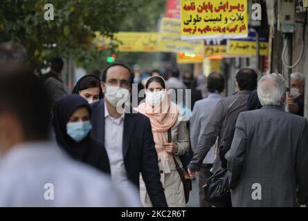 Eine iranische Frau, die eine schützende Gesichtsmaske trägt, um sich vor einer Infektion durch die neue Coronavirus-Krankheit (COVID-19) zu schützen, sieht zu, als sie am 26. Oktober 2020 entlang einer Straße im Geschäftsviertel von Teheran geht. (Foto von Morteza Nikoubazl/NurPhoto) Stockfoto