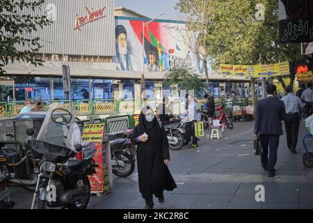 Eine verschleierte iranische Frau, die eine schützende Gesichtsmaske trägt, um sich vor einer Infektion durch die neue Coronavirus-Krankheit (COVID-19) zu schützen, geht am 26. Oktober 2020 entlang einer Straße im Geschäftsviertel von Teheran. (Foto von Morteza Nikoubazl/NurPhoto) Stockfoto