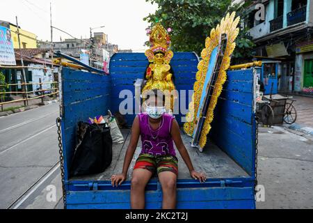 Ein Junge wartet darauf, ein Idol der Göttin Lakshmi vor der Festivalfeier Kalkutta, Indien, am 28. Oktober 2020 zu nehmen. Lakshmi puja ist das Fest der verehrenden Göttin Lakshmi, der hinduistischen Göttin des Reichtums und Wohlstands. Es wird am Vollmondtag nach Durga Dashami (dem letzten Tag von Durga puja) gefeiert. Anhänger glauben, dass am Tag der Lakshmi puja , die Göttin besucht ihre Anhänger nach Hause , bringt mit ihrem guten Reichtum und Wohlstand für die Familie. Die Frauen der Familie beten die Göttin Lakshmi an, nachdem sie ihr Haus gereinigt und Alpona auf den Boden gezeichnet haben, um die Göttin einzuladen Stockfoto