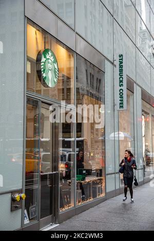 Eine Frau, die neben einem Geschäft vor einem Starbucks Coffee Shop in Midtown Manhattan mit Leuten geht. Starbucks Corporation ist die größte Kaffeehauskette der Welt, eine multinationale amerikanische Cafékette mit Hauptsitz in Seattle, Washington. NYC, Vereinigte Staaten von Amerika am 2020. Februar (Foto von Nicolas Economou/NurPhoto) Stockfoto