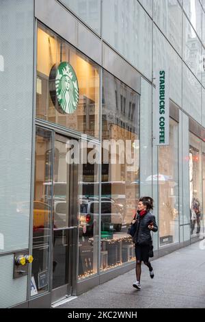 Eine Frau, die in Eile neben einem Laden vor einem Starbucks Coffee Shop in Midtown Manhattan läuft und Leute an ihnen vorbei laufen. Starbucks Corporation ist die größte Kaffeehauskette der Welt, eine multinationale amerikanische Cafékette mit Hauptsitz in Seattle, Washington. NYC, Vereinigte Staaten von Amerika am 2020. Februar (Foto von Nicolas Economou/NurPhoto) Stockfoto