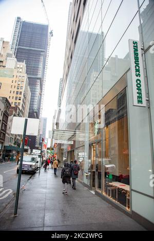 Ein Geschäft vor einem Starbucks Coffee Shop in Midtown Manhattan mit Menschen, die vorbei gehen und den Verkehr und Skyscrapper sichtbar. Starbucks Corporation ist die größte Kaffeehauskette der Welt, eine multinationale amerikanische Cafékette mit Hauptsitz in Seattle, Washington. NYC, Vereinigte Staaten von Amerika am 2020. Februar (Foto von Nicolas Economou/NurPhoto) Stockfoto