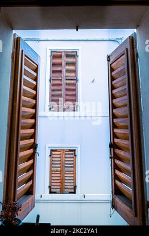Eine vertikale Aufnahme von hölzernen Fensterläden am Fenster Stockfoto