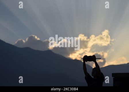 Eine Frau, die am Dienstag, den 27. Oktober 2020, Drachen von ihrem Dach in Kirtipur, Kathmandu, Nepal, fliegen lässt. (Foto von Narayan Maharjan/NurPhoto) Stockfoto