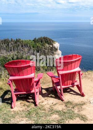 Blick auf Land's End (Bout du monde) in Forillons Park, Gaspe, Quebec, Kanada. Zwei rote Adirondack-Stühle für Menschen, um die Landschaft zu bewundern. Stockfoto