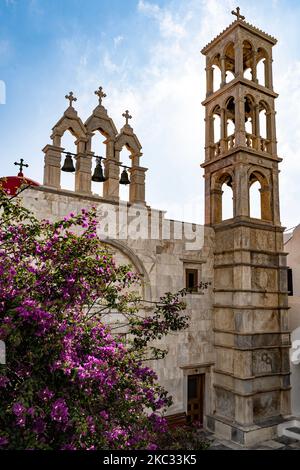 Eine Vertikale des Panagia Tourliani Klosters in Mykonos, Griechenland mit einem wunderschönen Anblick von blühenden Bäumen Stockfoto