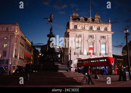 Am 6. November 2020 stehen Menschen neben dem Shaftesbury Memorial Fountain (gemeinhin als „Eros“ bekannt) des Piccadilly Circus in London, England. England begann gestern mit der zweiten nationalen Blockierung des Coronavirus, die der britische Premierminister Boris Johnson am vergangenen Samstag angekündigt hatte und begründete die Befürchtungen, dass covid-19 erneut drohte, den National Health Service (NHS) zu überfordern. Pubs, Bars, Restaurants und Geschäfte, die nicht unbedingt benötigt werden, müssen bis zum derzeit geplanten Ende des 2. Dezember geschlossen sein. Die Menschen wurden inzwischen gebeten, so weit wie möglich zu Hause zu bleiben, obwohl Schulen und andere Bildungseinrichtungen Stockfoto