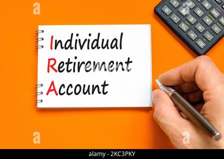 IRA-Symbol für individuelles Rentenkonto. Konzeptworte IRA individuelles Rentenkonto auf weißer Note auf einem schönen orangen Hintergrund. IRA für Unternehmen Stockfoto