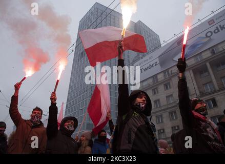 Während des polnischen Unabhängigkeitstages am 11. November 2020 in Warschau, Polen, halten Menschen Fackeln und winken polnische Fahnen. Nachdem Warschaus Bürgermeister Rafal Trzaskowski letzte Woche den Tag der Nationalen Unabhängigkeit verboten hatte, um die Covid-19-Pandemie einzudämmen, riefen die Organisatoren dazu auf, sich in Fahrzeugen zu beteiligen, aber trotzdem versammelten sich Menschen und marschierten mit Parolen und Flaggen. (Foto von Aleksander Kalka/NurPhoto) Stockfoto