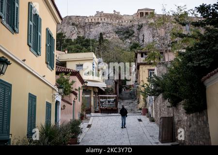 Ein Mann sah, wie er am 12. November 2020 während der zweiten COVID-19-Sperre in Griechenland auf einer leeren Straße mit der Akropolis von hinten in Athen, Griechenland, spazieren ging. (Foto von Nikolas Kokovlis/NurPhoto) Stockfoto