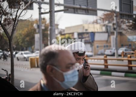 Ein Geistlicher, der eine Gesichtsmaske trägt, spricht auf seinem Smartphone, während er am 10. November 2020 inmitten des Ausbruchs der neuen Coronavirus-Krankheit (COVID-19) in der heiligen Stadt Mashhad in der Provinz Razavi Khorasan 891Km (554 Meilen) östlich von Teheran auf einer Straße entlang geht. Nachdem die iranischen Regierungen in der heiligen iranischen Stadt Mashhad und der Hauptstadt der Provinz Khorasan Razavi erneut rote Alarmbereitschaft angekündigt hatten, wurde der Gebrauch von Masken an öffentlichen Orten obligatorisch. (Foto von Morteza Nikoubazl/NurPhoto) Stockfoto