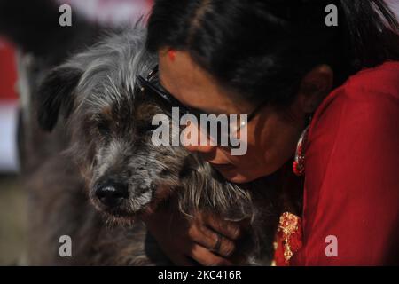 Sneha Shrestha, die Gründerin von Sneha's Care, umarmt den disable Dog, bevor sie Puja auf dem Kukur Tihar oder Dog Festival während der Prozession der Tihar-Feierlichkeiten in Kathmandu, Nepal, am Samstag, dem 14. November 2020, aufführte. Tihar ist ein hinduistisches Fest, das in Nepal 5 Tage lang gefeiert wird. Nepalesische Menschen verehren den Hund, füttern am zweiten Tag von tihar leckeres Essen. Dog ist ein vertrauenswürdiger Wächter des Menschen. Tihar-Marke als das Fest der Lichter, wie die Menschen schmücken ihre Bewohner mit verschiedenen Blumengirlanden, Öllampen und bunten Glühbirnen. (Foto von Narayan Maharjan/NurPhoto) Stockfoto