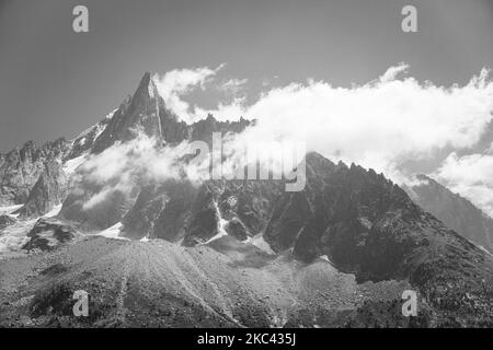 Eine Graustufenaufnahme von hohen felsigen Bergen in den Wolken Stockfoto