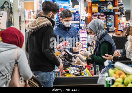 Am 16. November 2020 ging es in Istanbuls historischem Viertel Fatih mit Gesichtsmasken über das tägliche Leben und den Alltag, wo viele Einkäufer in Einkaufsviertel gehen und in öffentlichen Räumen spazieren gehen und dabei die Richtlinien des Coronavirus oder Covid-19 beobachten. Oben warten die Einwohner Istanbuls in einer Check-out-Schlange in einem Lebensmittelgeschäft im Stadtteil Fatih von Istanbul, Türkei. (Foto von Diego Cupolo/NurPhoto) Stockfoto