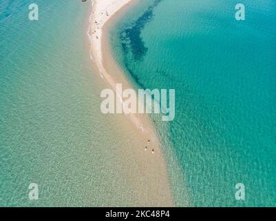 Luftaufnahme der exotischen Potamos - Epanomi Beach Sandbank in der Nähe der Stadt Thessaloniki von einer Drohne während der Pandemie des Coronavirus Covid-19 mit sozialen Distanzierungsmaßnahmen. Ein paar Sonnenschirme und Menschen werden gesehen, wie sie sich am Strand mit dem kristallklaren Wasser der Ägäis und des Mittelmeers entspannen. Der Epanomi Strand liegt in der Nähe der Stadt und des Flughafens, der für den tropischen Sandstrand, die Dünen, das Schiffswrack, die Sandbank und die Strandbars bekannt ist. Die Zahl der Touristen und Besucher in Griechenland und weltweit sank während der Pandemie-Ära, was die Tourismusbranche traf. E Stockfoto