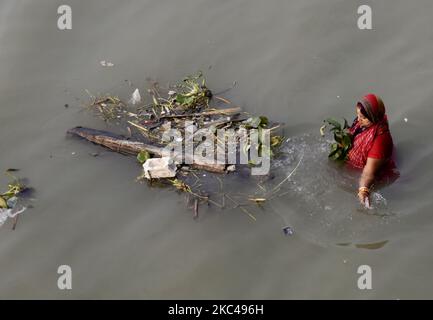 Eine Frau entfernt Müll, während sie während des Chhath-Puja-Festivals inmitten eines Coronavirus-Notfalls in Kalkutta, Indien, am 20. November 2020, den sonnengott anbetet. Das Chhath Festival, auch bekannt als Surya Pooja, oder Anbetung der Sonne, wird in mehreren Teilen der indischen Staaten beobachtet, die von der Bihari Gemeinschaft gefeiert werden, und sieht eifrige Anhänger, die den sonnengott an den Ufern von Flüssen oder kleinen Teichen anbeten, Und für die Langlebigkeit und Gesundheit ihres Ehegatten zu beten. (Foto von Indranil Aditya/NurPhoto) Stockfoto