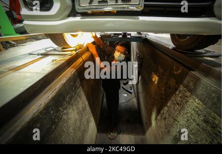 Ein Sri-lankischer Arbeiter, Raja, trägt einen Gesichtsschutz und eine Gesichtsmaske und ersetzt einen Reifen in einem Reifenladen, Nandula Radpflege, in Colombo, Sri Lanka. 20. November 2020. Sri Lanka übertraf laut Gesundheitsministerium 19000 bestätigte Covid-19-Patienten mit insgesamt 73 Covid-19-bezogenen Todesfällen und 12903 Genesungen bis Freitag (20). Generalleutnant Shavendra Silva, Chef der Armee Sri Lankas und Leiter des Nationalen Operationszentrums zur Prävention des COVID-19-Ausbruchs (NOCPCO), erklärte, dass die Task Force des Präsidenten auf COVID-19 zusammen mit den srilankischen Gesundheitsbehörden die Lage auf der isola einschätzen Stockfoto