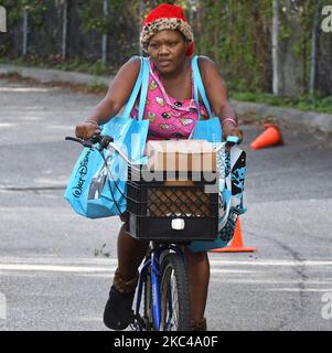 Eine Frau auf einem Fahrrad trägt Lebensmittel, die von der Second Harvest Food Bank of Central Florida und der Stadt Orlando bei einer Veranstaltung zur Lebensmittelverteilung an der Jones High School am 20. November 2020 in Orlando, Florida, gespendet wurden. Mit dem Anflug von Thanksgiving benötigen Tausende von Familien in der Umgebung von Orlando aufgrund massiver Entlassungen in lokalen Themenparks und der Tourismusindustrie Nahrungsmittelhilfe. (Foto von Paul Hennessy/NurPhoto) Stockfoto