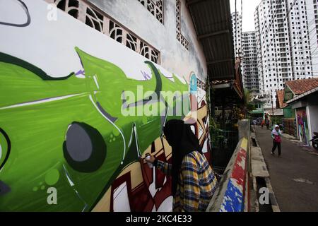 Ein indonesischer lokaler Künstler zeichnete Graffiti auf die Wände der Häuser, damit die Bewohner das Dorf, das Zentrum der schriftlichen Batikhandwerker in Batik Village, Cibuluh, Bogor City, West Java, Indonesien, dekorieren und verschönern konnten. Am 22. November 2020. (Foto von Adriana Adie/NurPhoto) Stockfoto