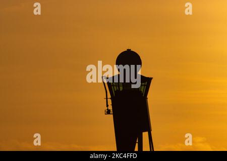 Goldene Stunde bei Sonnenaufgang und Sonnenaufgang mit warmen Himmelsfarben der magischen Stunde am internationalen Flughafen Amsterdam Schiphol AMS EHAM in den Niederlanden. Frühmorgendliche Aufnahmen der Luftfahrtindustrie mit der Silhouette des Kontrollturms und des Landeflugzeugs im bunten europäischen Skyscape. 22. November 2020 (Foto von Nicolas Economou/NurPhoto) Stockfoto