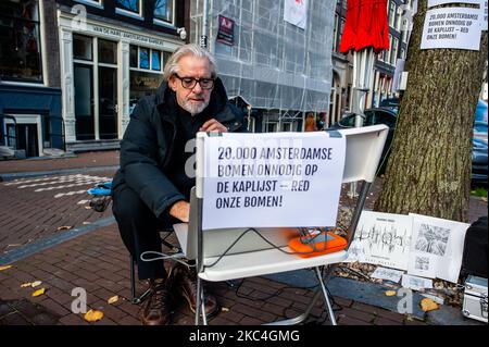 Der niederländische Künstler und Musiker Bert Barten produziert Musik, indem er ein Audiosystem an den Baum hinter ihm und von dort an seinen Computer anbringt, während der musikalischen Proteste gegen den Baumschnitt im Zentrum von Amsterdam am 23.. November 2020. (Foto von Romy Arroyo Fernandez/NurPhoto) Stockfoto