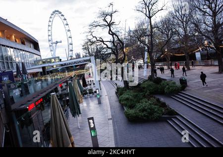 Am 23. November 2020 laufen die Menschen am nahe verlassenen Südufer der Themse entlang, wo normalerweise ein jährlicher Weihnachtsmarkt stattfindet. In ganz England bleiben nicht unbedingt erforderliche Geschäfte sowie Bars, Restaurants und andere Gastgewerbebetriebe im Rahmen der zweiten nationalen Sperre des Coronavirus geschlossen, die am 5. November begonnen wurde und am 2. Dezember ausläuft. (Foto von David Cliff/NurPhoto) Stockfoto