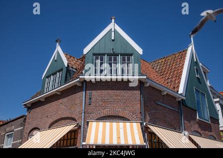 Alltag in Volendam Traditionelles Fischerdorf mit holländischer Architektur in Nordholland in der Nähe von Amsterdam in den Niederlanden. Volendam hat einen Hafen und ist ein beliebtes Ziel und Touristenattraktion im Land. Es gibt alte Fischerboote, traditionelle Kleidung der Einheimischen, Fährfahrt nach Marken, Museen, Käsefaktroy, Cafe und Souvenirläden am Wasser und einen kleinen Strand. Es gibt Häuser entlang der Küste und einen Yachthafen in der Nähe für Touristen und Einheimische als Besucher, so dass der Tourismus das Haupteinkommen für die Gemeinde ist. Volendam wurde in vielen aktuellen Filmen gezeigt. Volendam - Die Niederlande Stockfoto