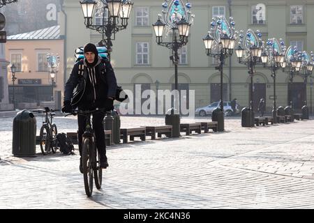 Auf seinem Byke auf dem kleinen Marktplatz in der Krakauer Altstadt wird ein Delivary-Mann gesehen, als die Stadt unter teilweiser Coronavirus-Sperre neue Weihnachtsdekorationen anlegt, 26. November 2020. Die Altstadt von Krakau ist in der Regel sehr voll mit Touristen, nicht es bleibt weitgehend verlassen wegen Covid-19 Einschränkungen. (Foto von Dominika Zarzycka/NurPhoto) Stockfoto