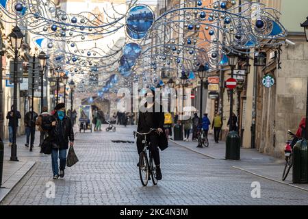 Passanten in Schutzmasken werden auf der Florianska Straße am Hauptmarkt in der Krakauer Altstadt gesehen, während die Stadt unter teilweiser Coronavirus-Sperre neue Weihnachtsdekorationen anzieht, 26. November 2020. Die Altstadt von Krakau ist in der Regel sehr voll mit Touristen, nicht es bleibt weitgehend verlassen wegen Covid-19 Einschränkungen. (Foto von Dominika Zarzycka/NurPhoto) Stockfoto