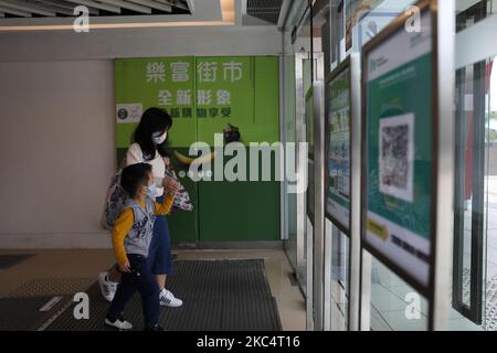 Am 28. November 2020 in Hongkong, China, werden Frauen und ein Junge mit Gesichtsmasken an einem Leave Home vorbeilaufen, QR-Code speichern und am Eingang eines Einkaufszentrums vorbeigehen sehen. Die Regierung von Hongkong hat eine neue App „Leave Home Save“ eingeführt, die es Benutzern ermöglicht, QR-Codes an verschiedenen Orten in Hongkong zu scannen, um ihre Bewegungen aufzuzeichnen und den Benutzer darüber zu informieren, wenn der Ausbruch von Covid-19 an einem der Orte stattgefunden hat, an denen sie teilgenommen haben Besucht, hat die Regierung auch angeordnet, dass Restaurants müssen sich registrieren und zeigen ihren QR-Code , Hongkong erlebt derzeit eine neue Welle von Covid-19 Fälle Reporti Stockfoto