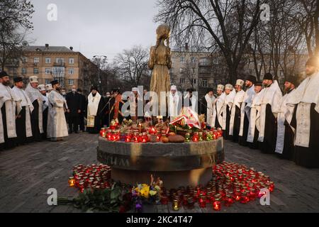 Priester verschiedener christlicher Konfessionen feiern einen Gedenkgottesdienst, während Menschen während der Trauerveranstaltung in Kiew, Ukraine, am 28. November Kerzen anzünden und Blumensträuße aus den Ohren und aus dem arrowwood zum Denkmal der großen Hungeropfer legen. 2020.die Ukraine ehrt das Gedenken an die Opfer der Hungersnöte und der Großen Hungersnot (Holodomor) von 1932 bis 1933, als 4,5 Millionen Ukrainer, darunter 600.000 ungeborene Kinder, vom sowjetischen Regime unter Joseph Stalin verhungert wurden. (Foto von Sergii Chartschenko/NurPhoto) Stockfoto